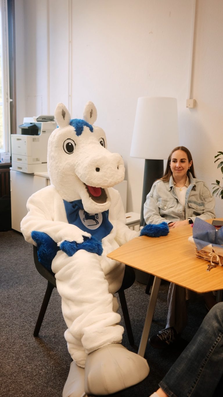 Maskottchen Öfi sitzt im Büro